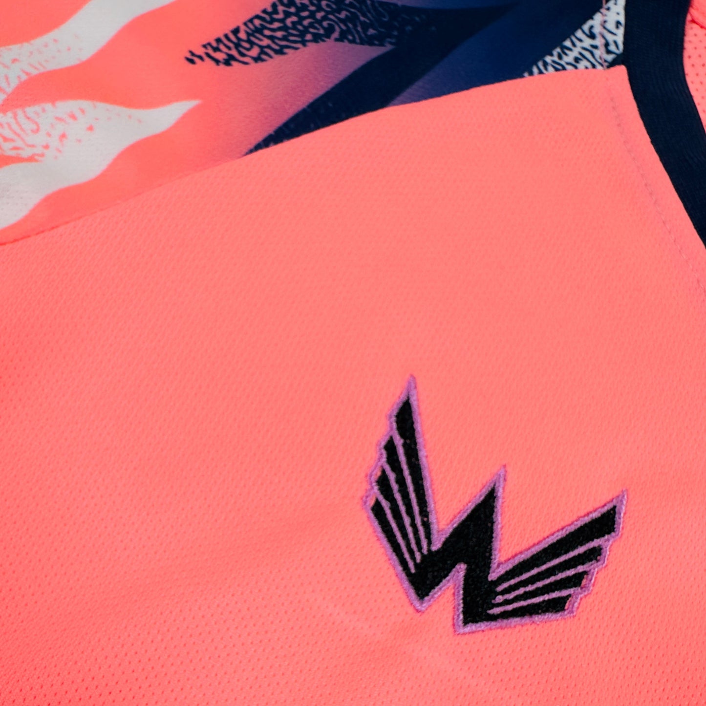 Close-up of a pink fabric with a black and white logo on a multicolored background